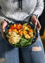 Woman holding a basket of vegetables that are keto friendly.